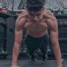 A muscular young man doing push ups in a modern gym setting